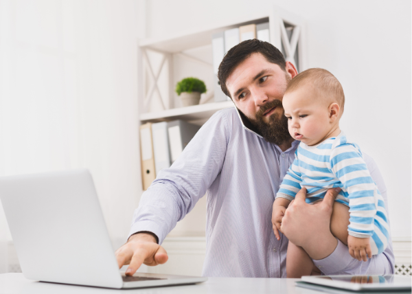 tata na rynku pracy - ojciec z małym dzieckiem na rękach przed laptopem