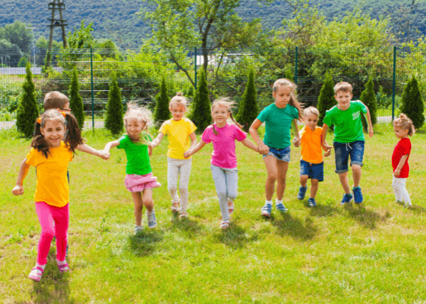opieka nad dziećmi w wakacje - dzieci bawiące się na trawie